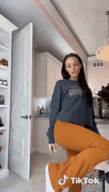 a woman wearing a sweater that says alaska on it stands in front of a door
