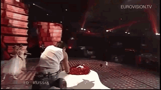 a man sitting on a stage with eurovision.tv on the bottom right