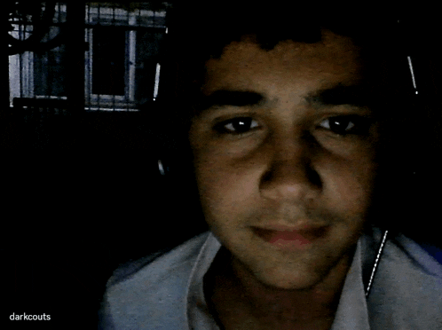 a young man 's face is shown in a dark room with the words darkscouts written on the bottom