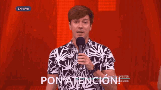a man in a black and white shirt is holding a microphone and says pon atencion