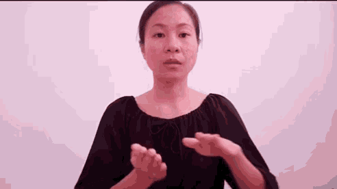 a woman is making a gesture with her hands while wearing a black shirt .