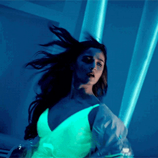 a woman in a white dress is dancing in front of a blue wall