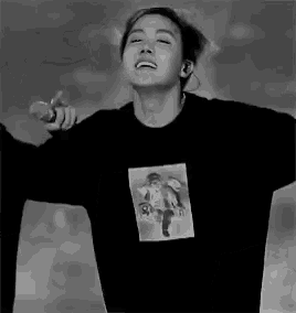 a black and white photo of a young man wearing a black sweatshirt with a picture of an angel on it .