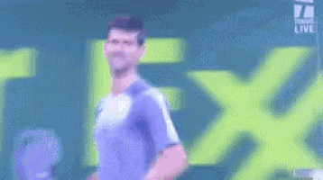 a man is holding a tennis racquet in front of a green sign that says arez