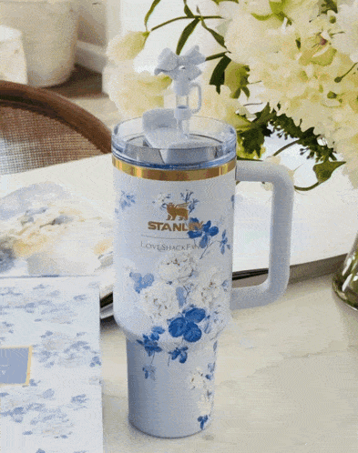 a blue and white floral stanley loveshack fan mug sits on a table