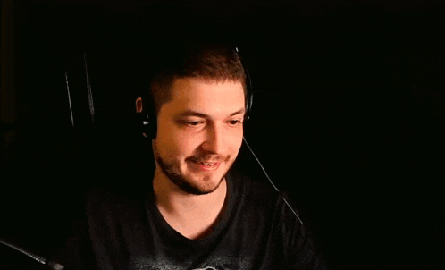 a man with a beard is wearing headphones and looking at the camera while a hand is behind him .