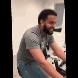 a man with a beard is riding an exercise bike .