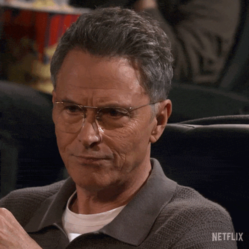 a man wearing glasses is sitting in a netflix movie theater