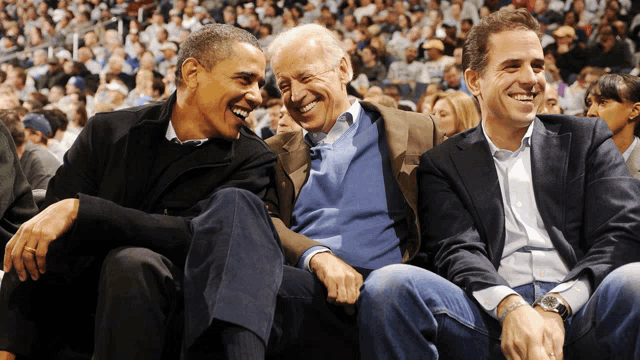 barack obama and joe biden are sitting in the stands at a basketball game