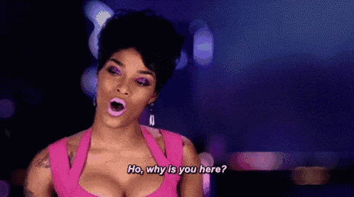 a woman in a pink dress is standing in front of a purple background and talking .
