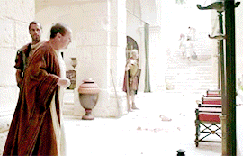 a man in a robe is standing in a courtyard with other men