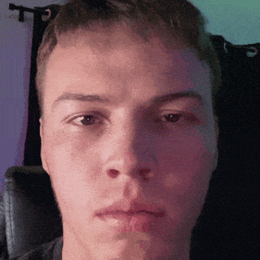 a close up of a man 's face with a purple curtain in the background