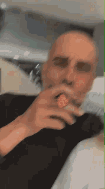 a man in a black shirt is smoking a cigarette in a blurry photo