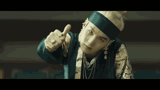 a man wearing a headband and earrings is pointing at the camera