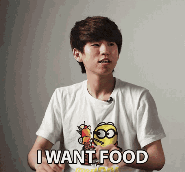 a boy wearing a white shirt with a minion on it says i want food
