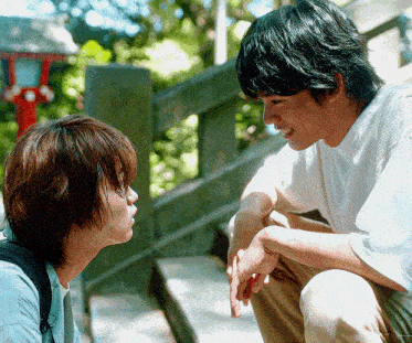 two young men are sitting next to each other and talking to each other
