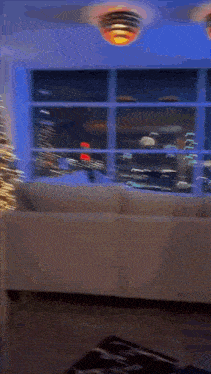 a man is standing in a living room next to a christmas tree