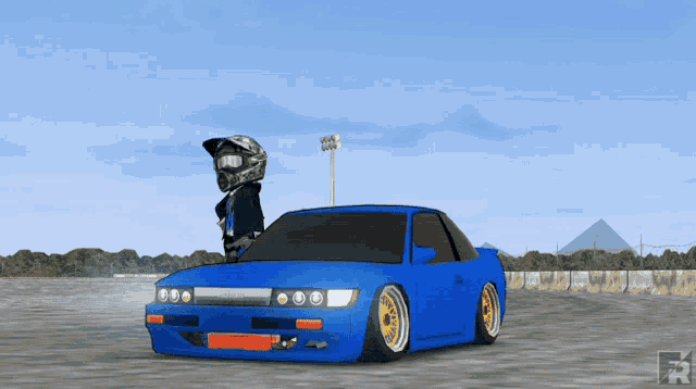 a person wearing a helmet and goggles stands next to a blue car