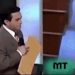 a man in a suit is holding a piece of paper in front of a sign that says mit