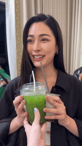 a woman is holding a green drink with a straw