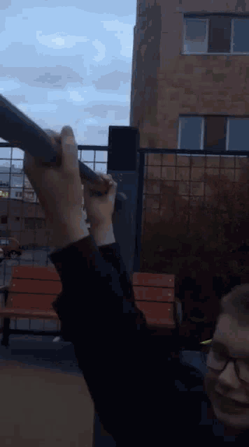 a person wearing glasses is holding a pole in a park