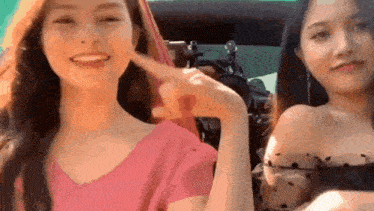 two women are sitting next to each other in a car and one is pointing at the other 's face .