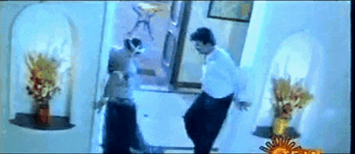 a man and a woman are dancing in a room with flowers on the wall .