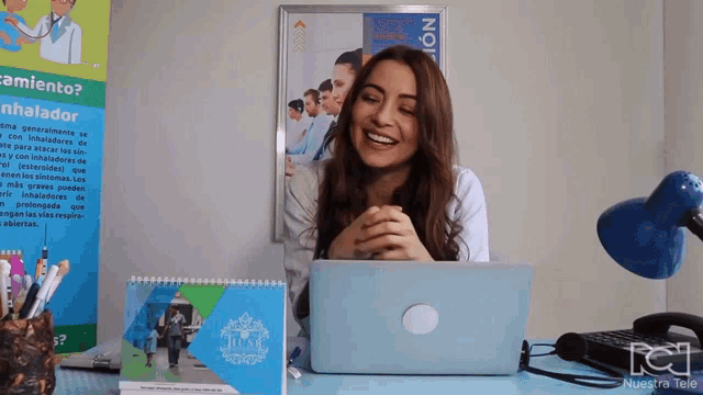 a woman sitting at a desk with a laptop and a calendar that says " nuestra tele "