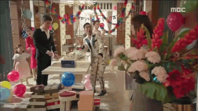 a group of people are standing in a room decorated with balloons and flowers with the word mbc on the bottom