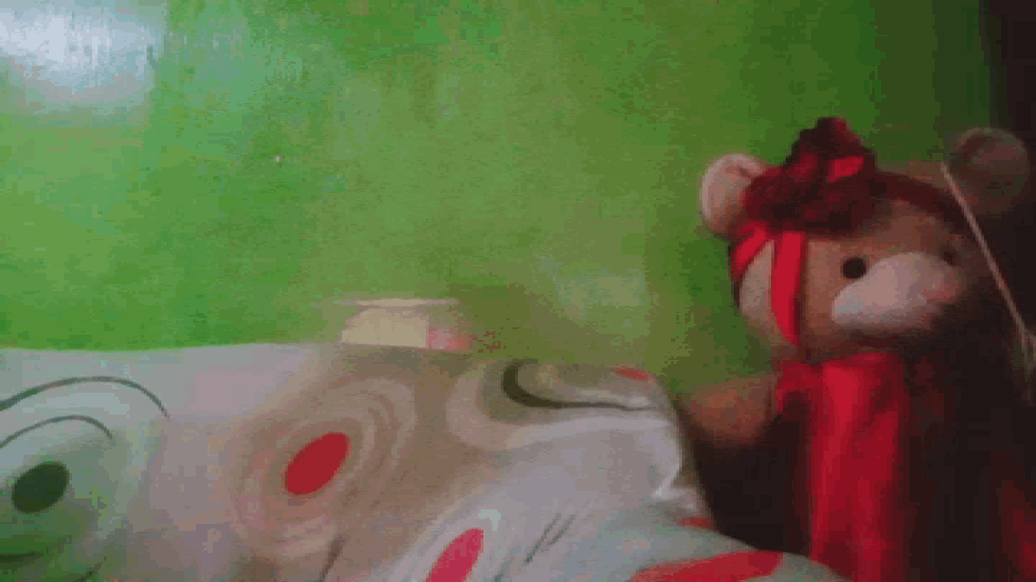 a teddy bear laying on a bed with a green background