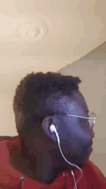 a man wearing headphones and a red hoodie looks to the side