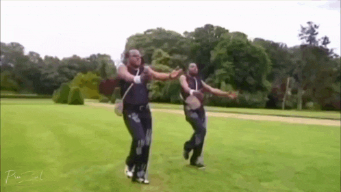two men are dancing in a grassy field with trees in the background and the word pixel on the bottom