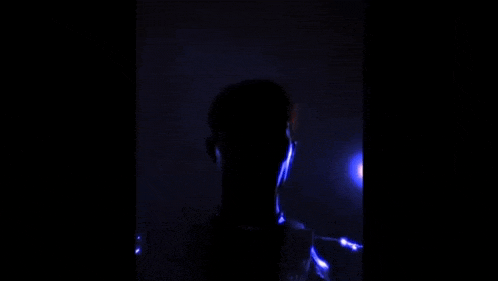 a silhouette of a person in the dark with a blue light behind them .