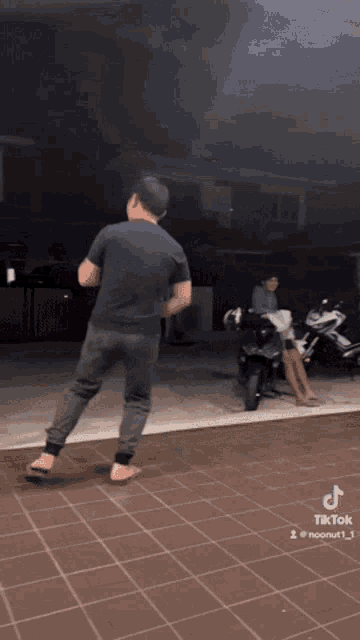 a man is standing on a tiled floor in front of a motorcycle and a woman