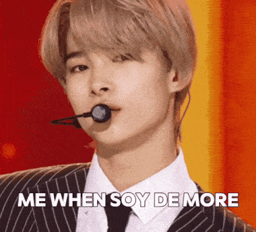 a man wearing a suit and tie is holding a microphone in his mouth and says me when soy de more