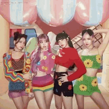 a group of girls are posing for a picture in front of a colorful background .