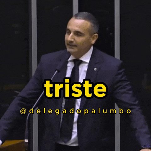 a man in a suit and tie is speaking into a microphone with the words e ansioso behind him