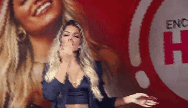 a woman blows a kiss in front of a sign that says " enrique h "