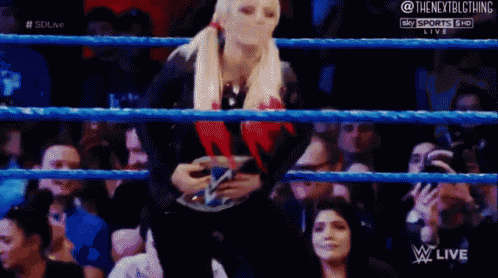 a woman is standing in a wrestling ring holding a wwe belt .