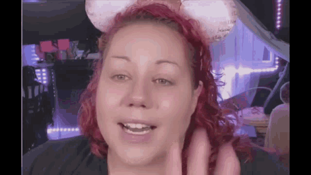 a woman with red hair wearing a headband that says minnie mouse ears