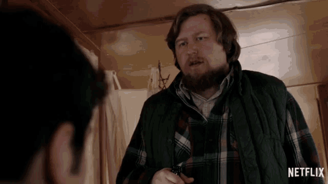 a man in a plaid shirt is holding a gun in front of a netflix ad