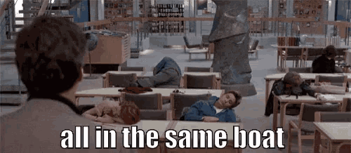 a man is standing in a library looking at a group of people sleeping at tables .