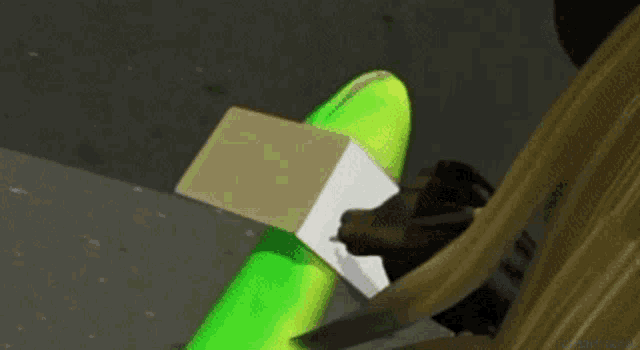 a person is sitting on the ground with a green balloon and a cardboard box .