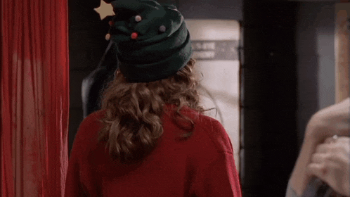 a woman wearing a green christmas tree hat and a red sweater .