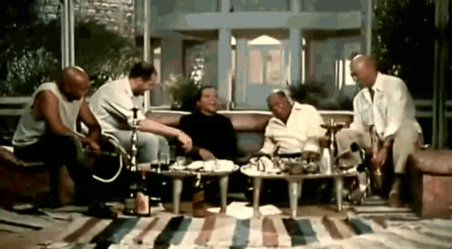a group of men are sitting on a couch talking to each other while smoking hookahs .