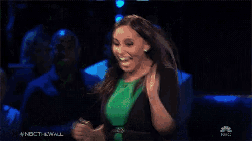 a woman in a green dress is dancing on a stage in front of a crowd .