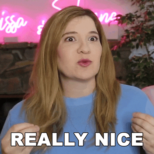 a woman in a blue shirt says really nice in front of a pink sign