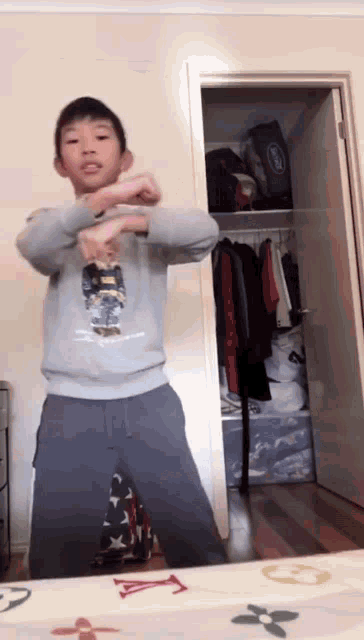 a young boy wearing a polo bear sweatshirt stands in front of a closet