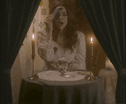 a woman is sitting at a table with candles and a sign that says i see your bank account is