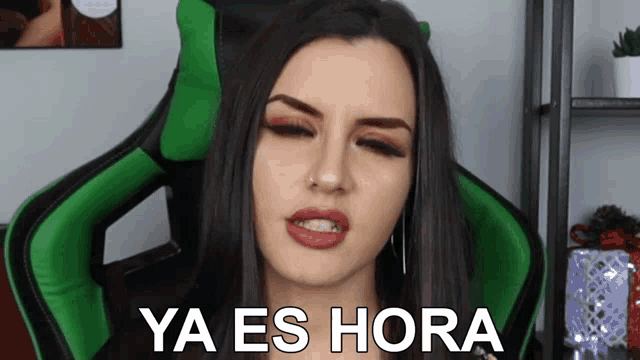 a woman sits in a green chair with the words ya es hora written on her face